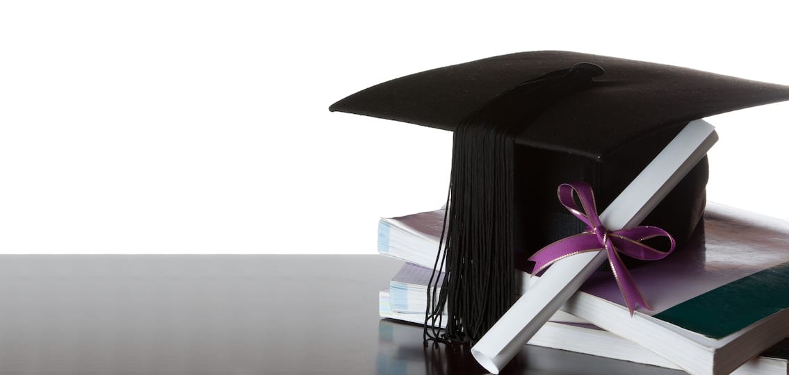 graduate certificate and graduate cap on a stack of books isolated on white