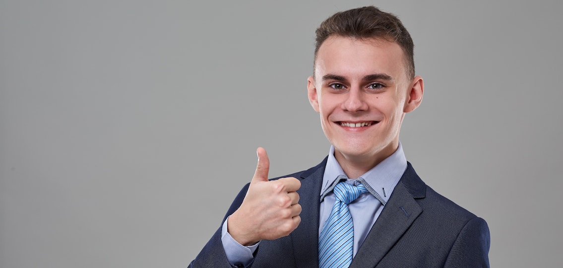 Young man in classic business suit, showing thumbs up sign
