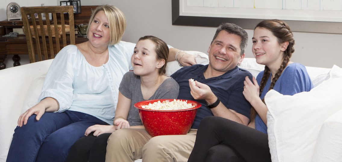 Family watching television together on couch on family movie night