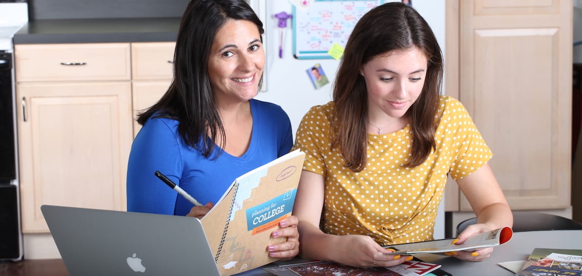 mom writing in a notebook planning for college while daughter looks at a magazine