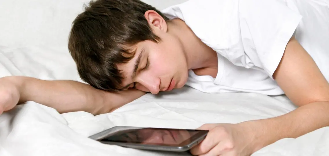 Tired Young Man Sleeps with Tablet Computer on the bed
