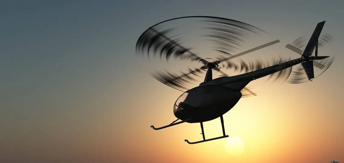 Civilian helicopter in the sky at sunset