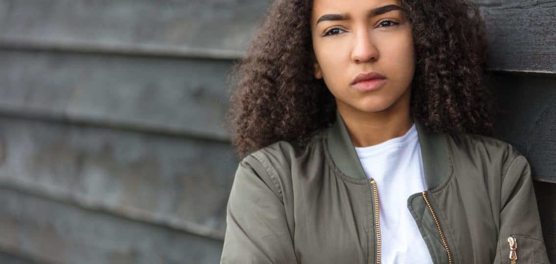 teenager female young woman outside wearing a green bomber jacket looking sad depressed or thoughtful