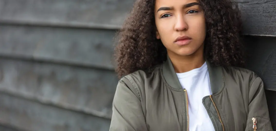 teenager female young woman outside wearing a green bomber jacket looking sad depressed or thoughtful
