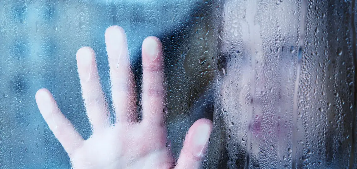 hand of young woman melancholy and sad at the window in the rain