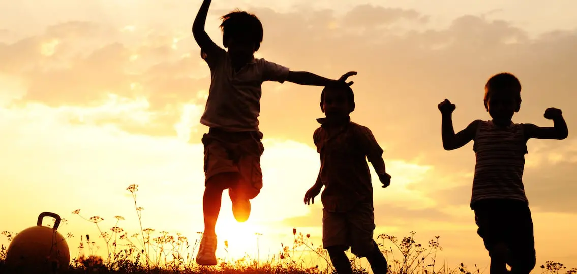 Silhouette, group of happy children playing on meadow