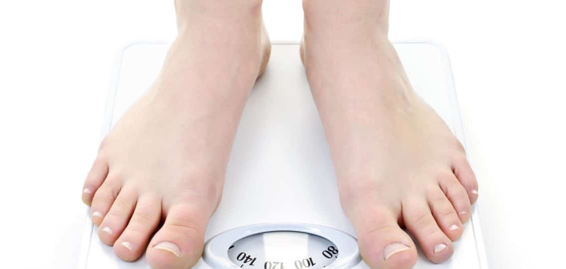 Bare feet standing on bathroom scale 118 pounds underweight