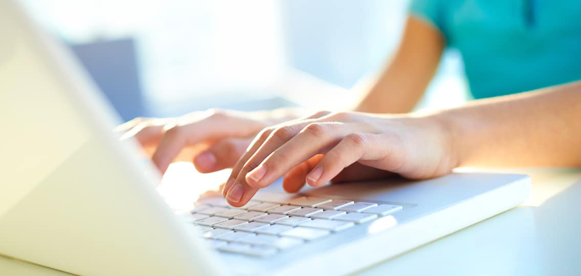 Close-up shot of a female learner typing on the laptop keyboard
