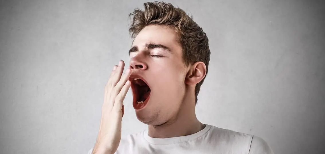 Teen boy Yawning with a gray background