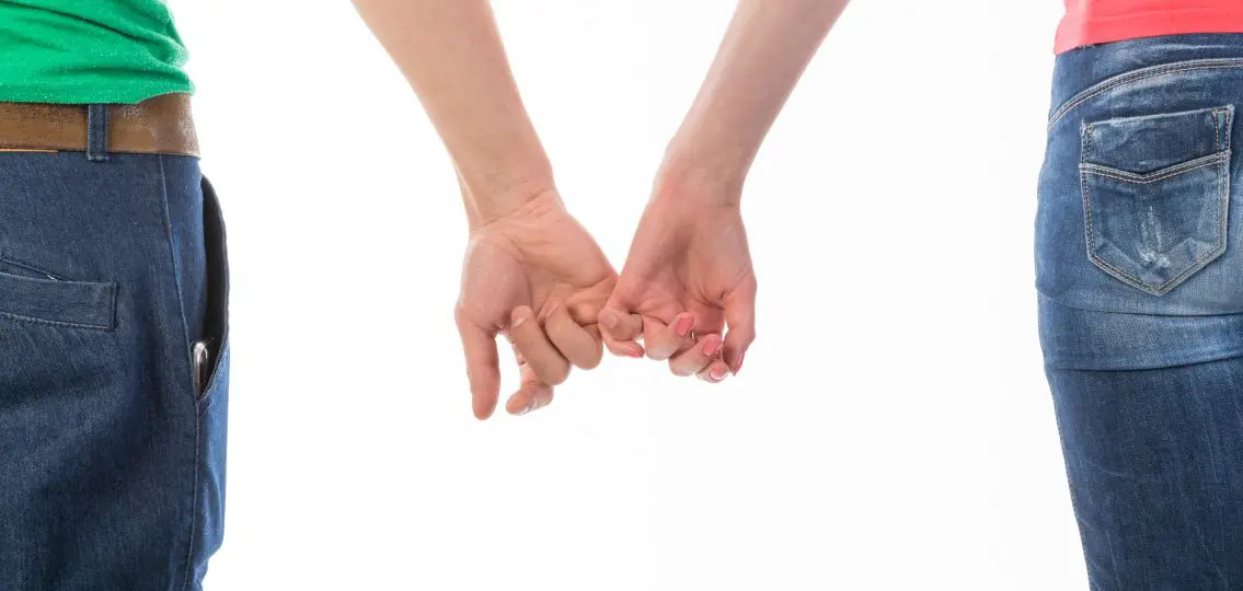 Cropped rear view image of a man and woman in casual clothing holding hands isolated on white