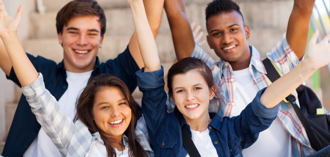 excited high school students with arms outstretched outdoors