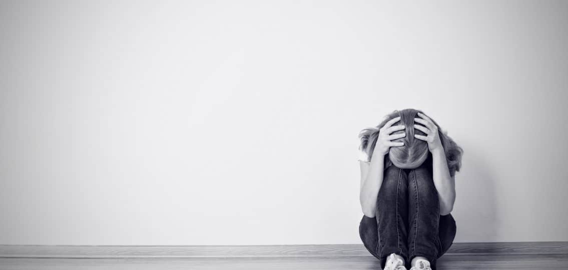 girl sits in a depression on the floor near the wall monochrome