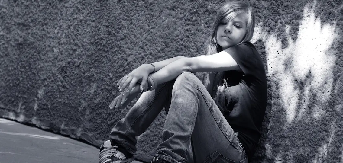 black and white girl with skateboard sitting against a wall. Shadow on a wall as an angle wing