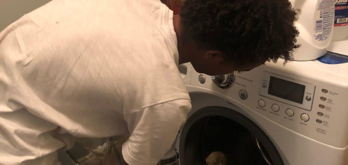 a teenage boy loading laundry into a washing machine