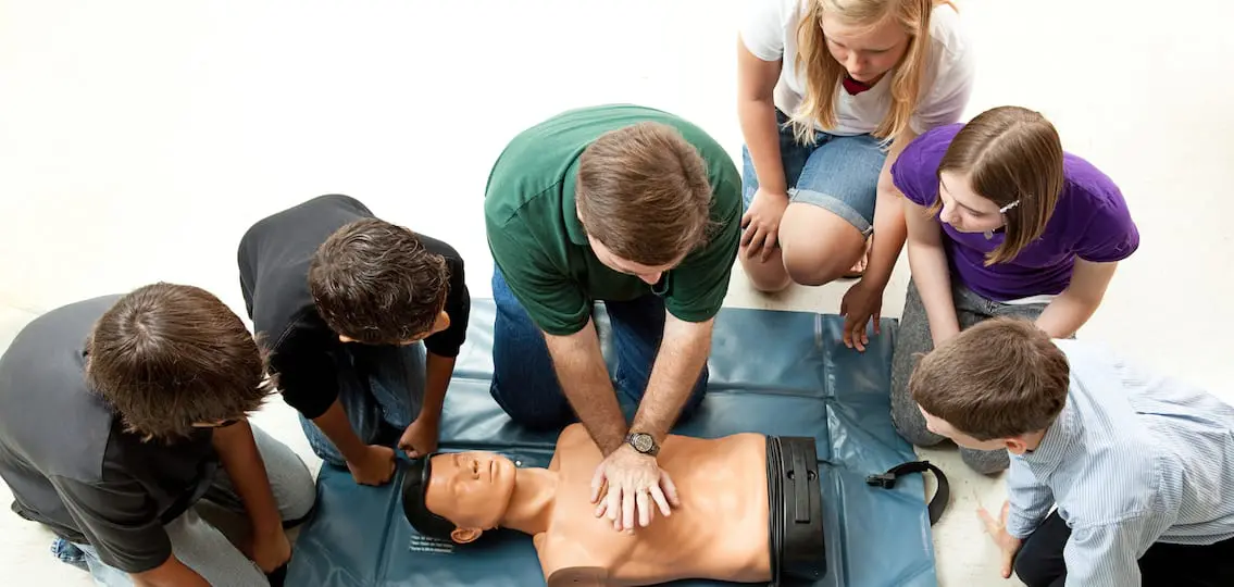 Group of teenagers learing CPR (cardiopulmonary resuscitation) in school.