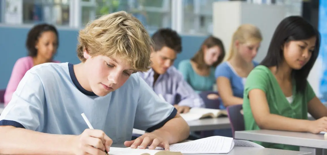 teenage freshman working on his homework during class