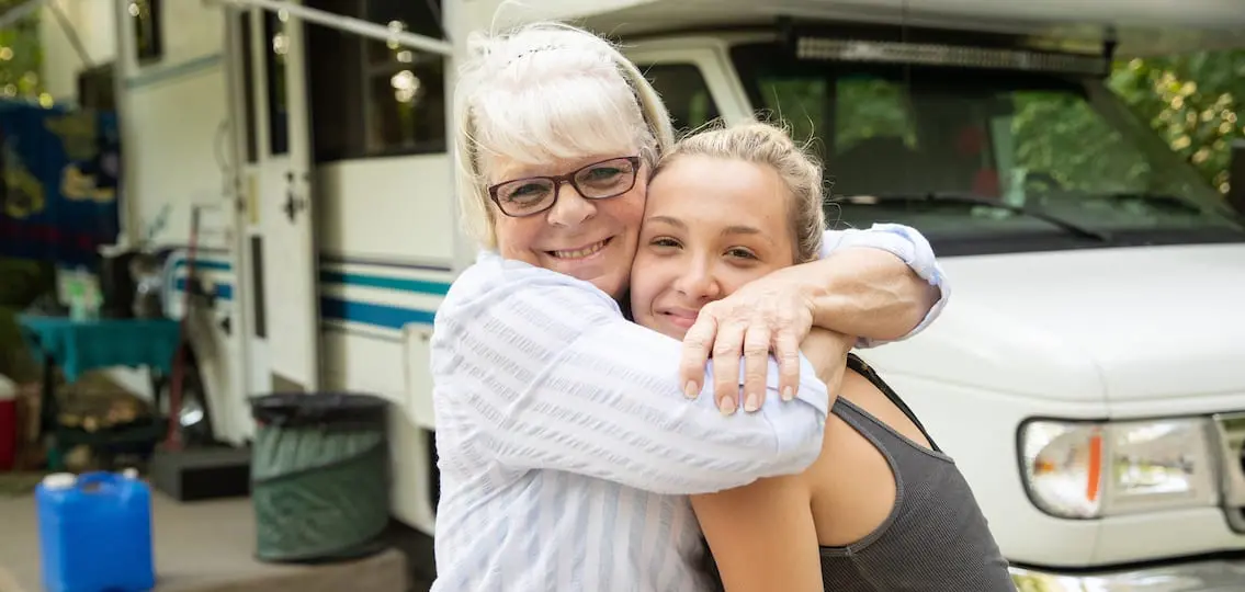 Grandma Hugging Teenage Granddaughter in front of an rv