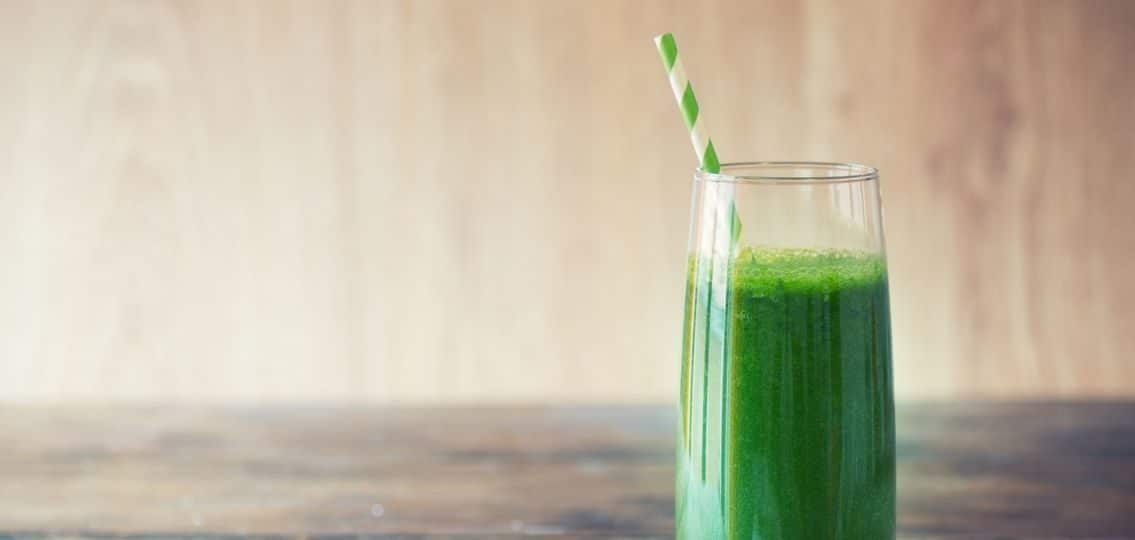 a green smoothie isolated in front of a wooden wall