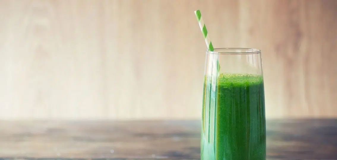 a green smoothie isolated in front of a wooden wall