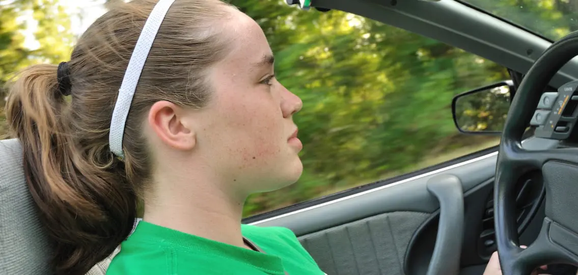 Teen Girl Driving a Convertible Car gripping the steering wheel