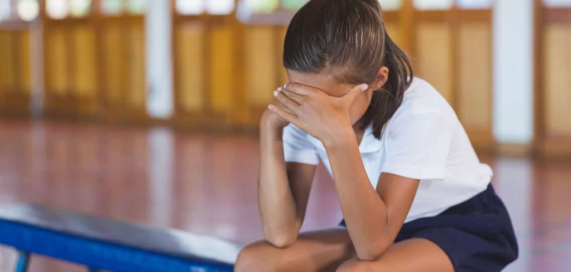 Crying girl in gym class covering face