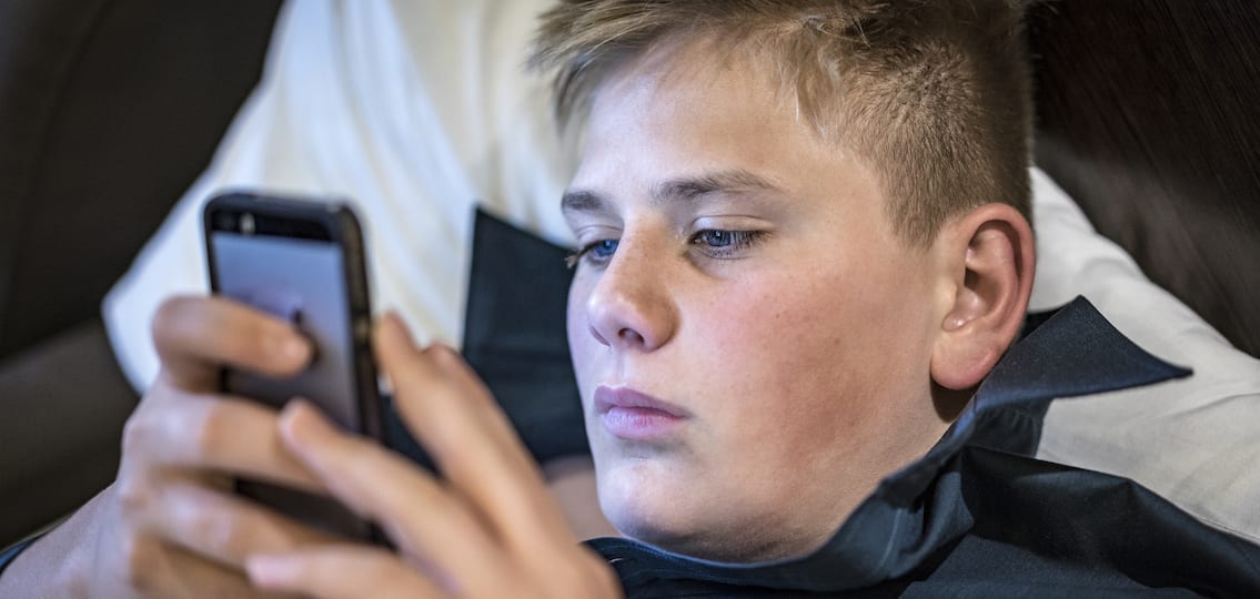 Young teenage boy reading a text message on his mobile phone