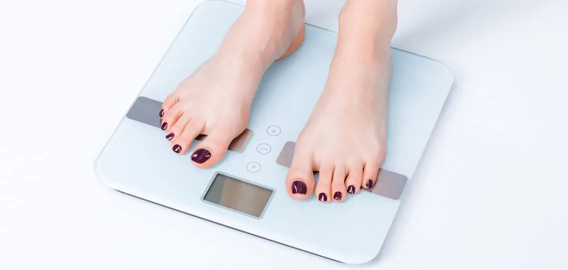 Teen girl standing on scale checking weight