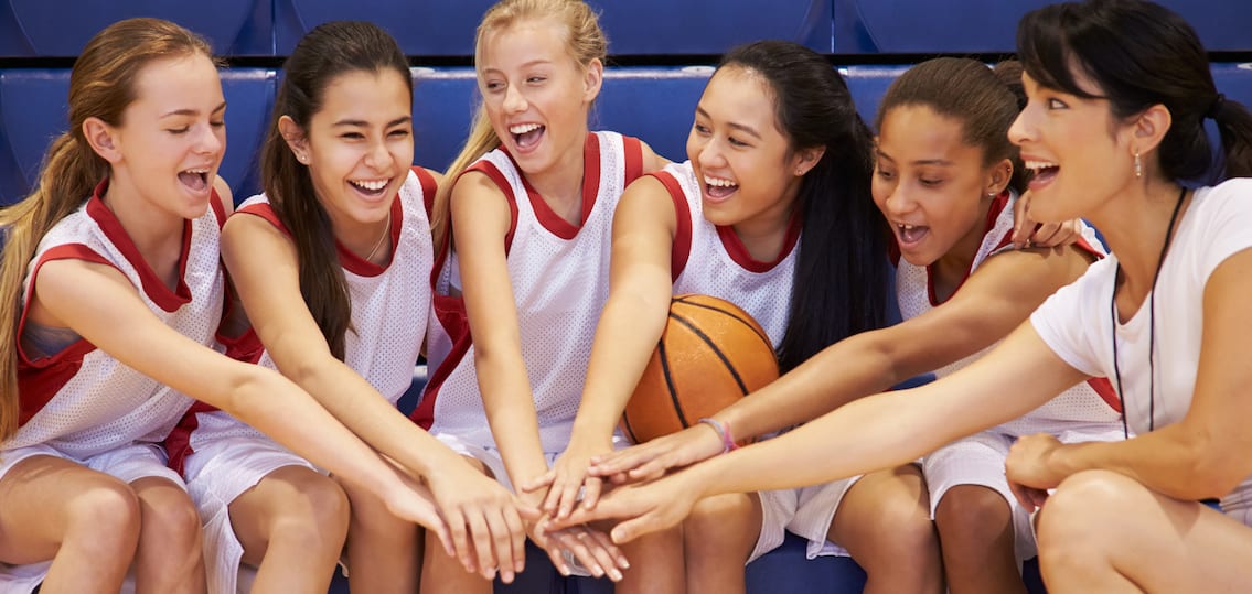 meisjes en coach voor basketbalwedstrijd op tribune handen in kring