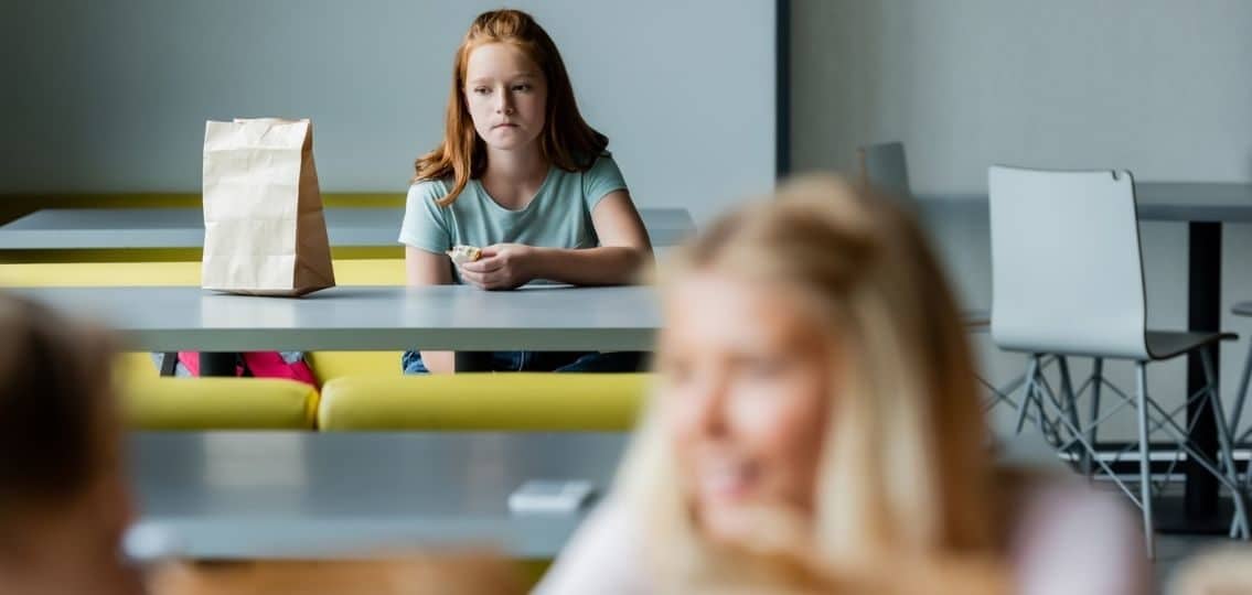 teen girl being left out sitting by herself at lunch