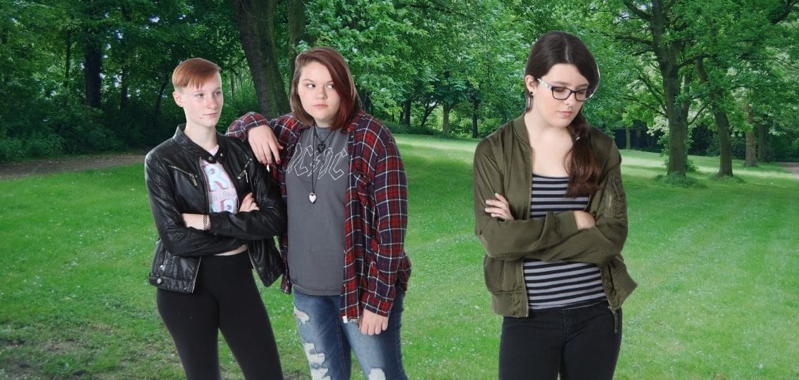 a teenage girl being left out by her mean friends in a park