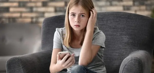 Sad Teenage Girl With Smartphone At Home