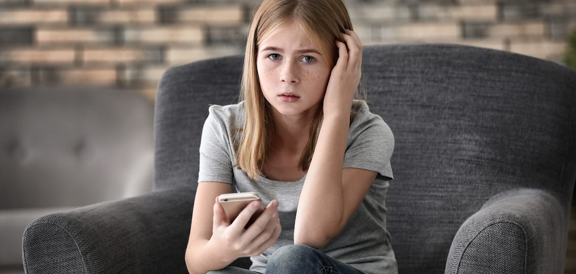 Sad Teenage Girl With Smartphone At Home