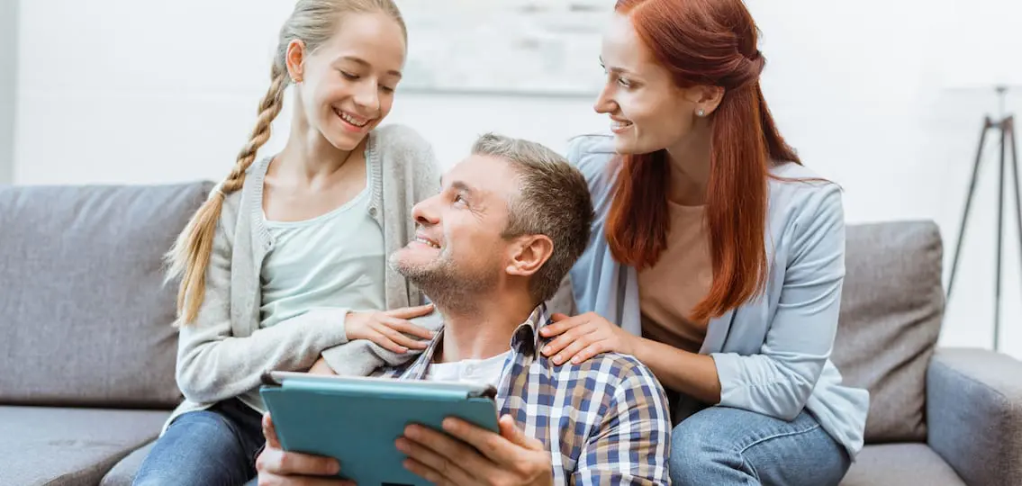 Family On Tablet smiling together on a couch