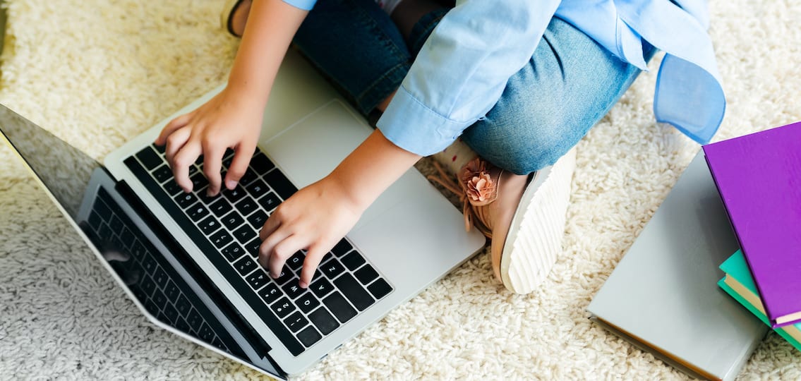 close up teenage girl working on her computer on a carpet