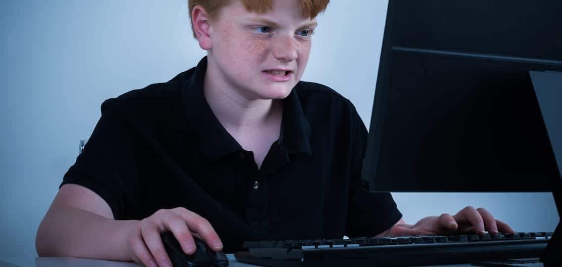 Angry Boy Sitting On Chair Working On Computer At Home