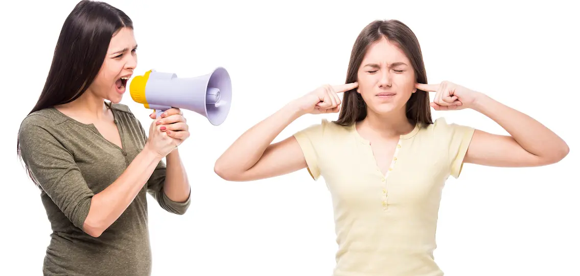 Teen closed his ears with his hands while her mom yells at her with a megaphone.