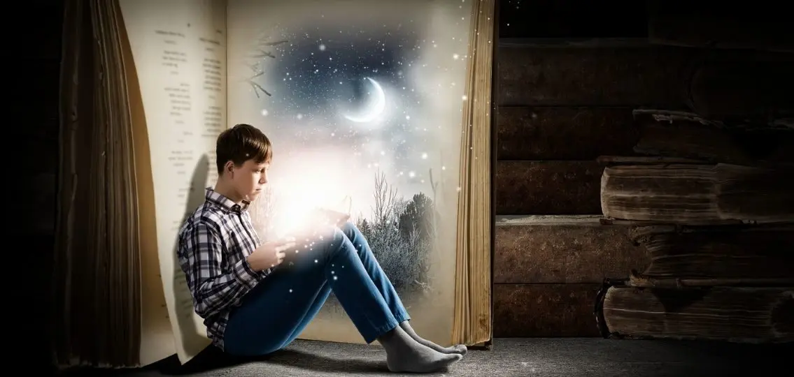 teen boy reading in front of a giant open book