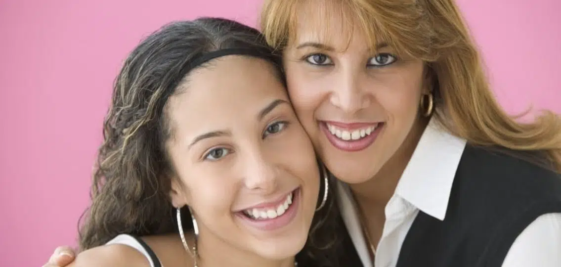 smiling mom and daughter hugging cheek to cheek