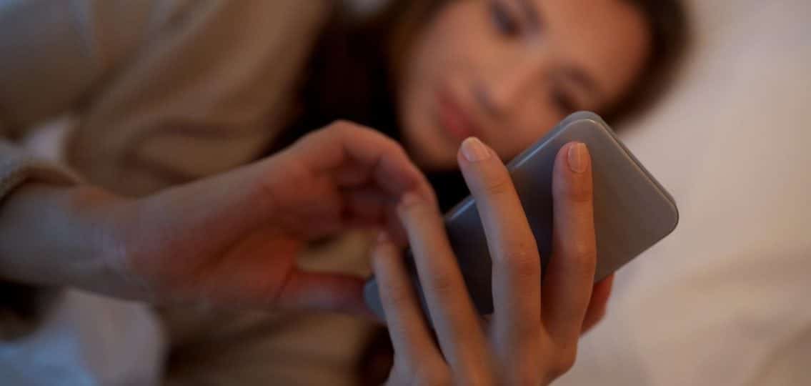 close up teen girl in bed on phone blurred