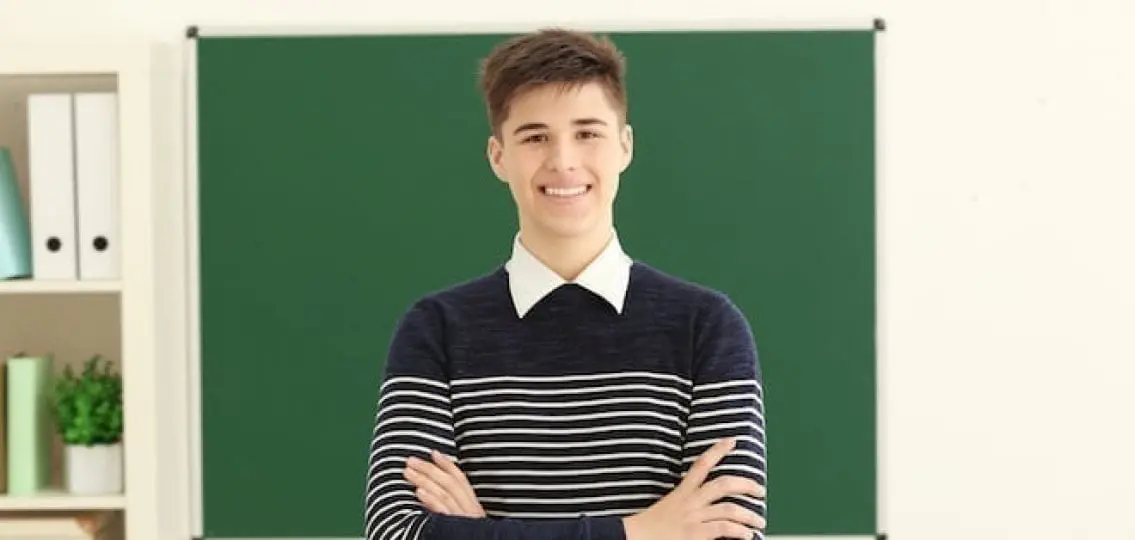 smiling confident teen boy in front of a blackboard