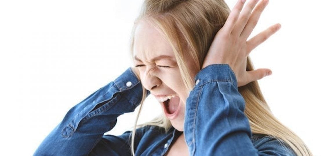 screaming stressed teenage girl covering her ears on a white background