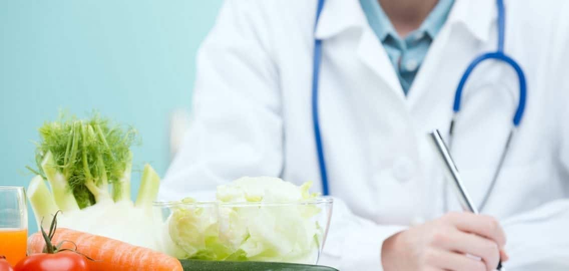 doctor writing on a clipboard with piles of vegetables