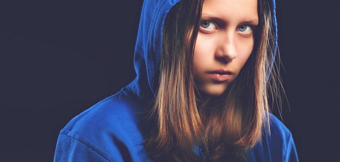 angry negative teenage girl in a hoodie glaring at the camera