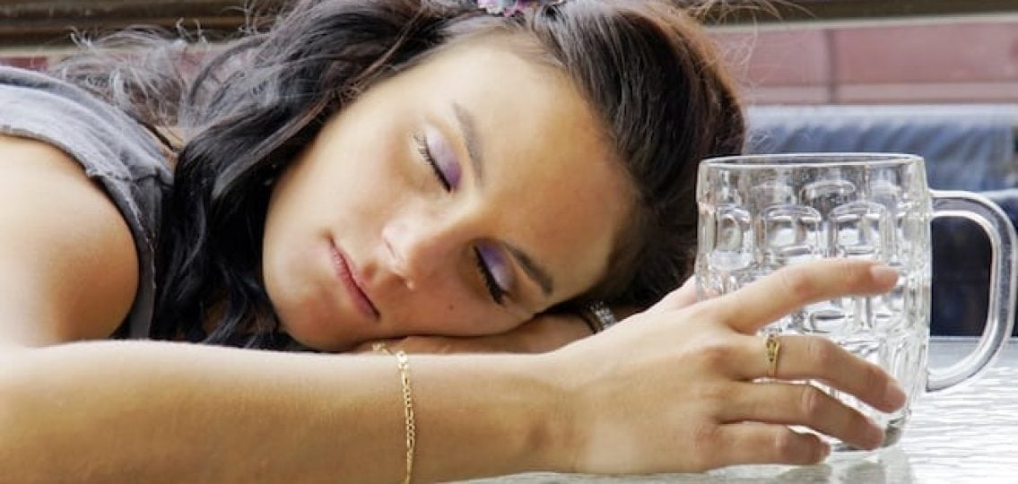 unconscious girl with an empty beer mug lying on a table