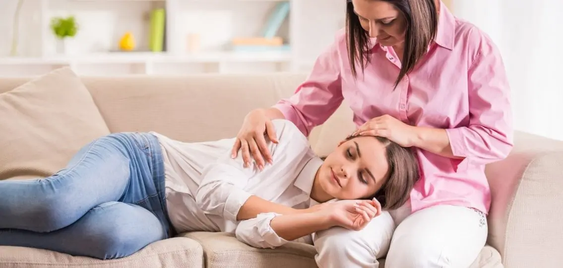 an immature teen girl lying her head in her mom's lap