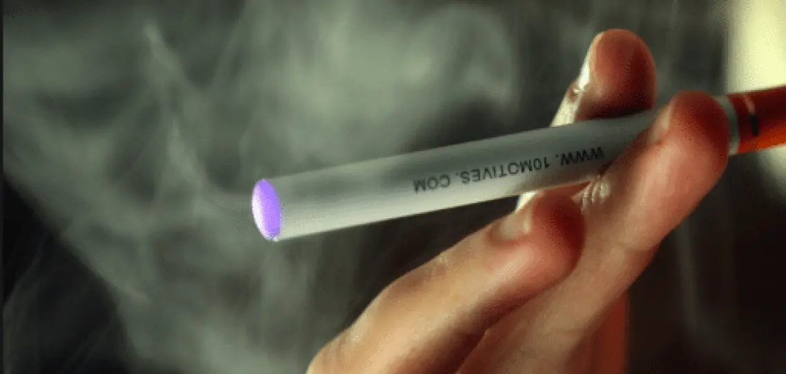 a close up of an e-cigarette being smoked surrounded by vape smoke