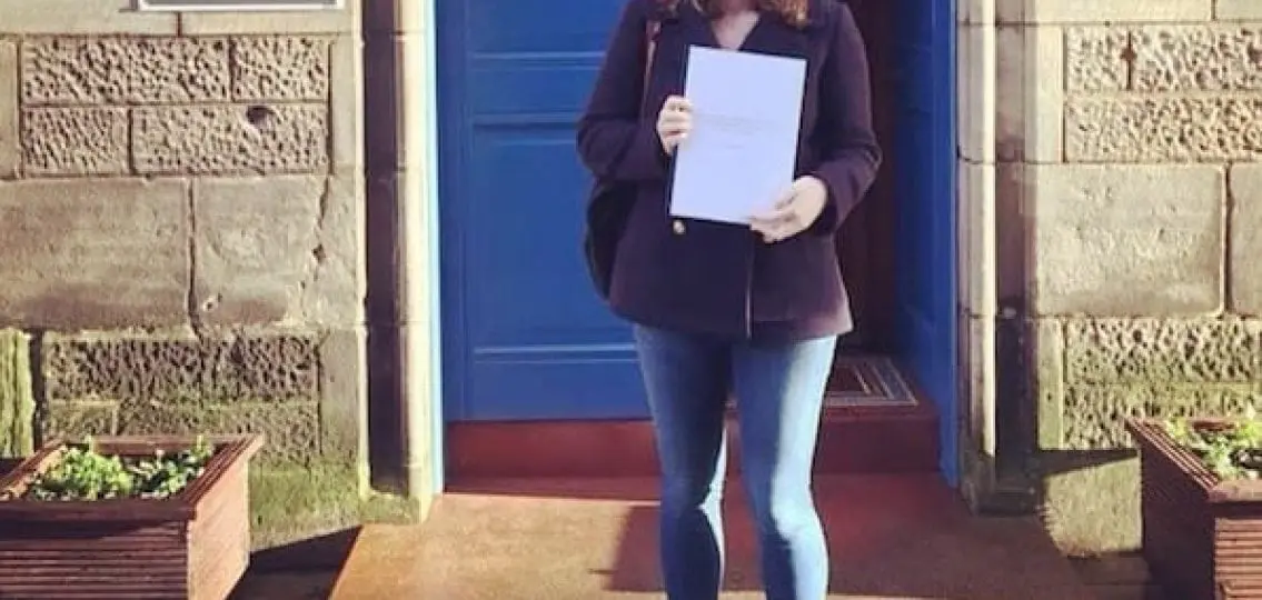 a college student in front of the Department of Social Anthropology at St. Andrews University