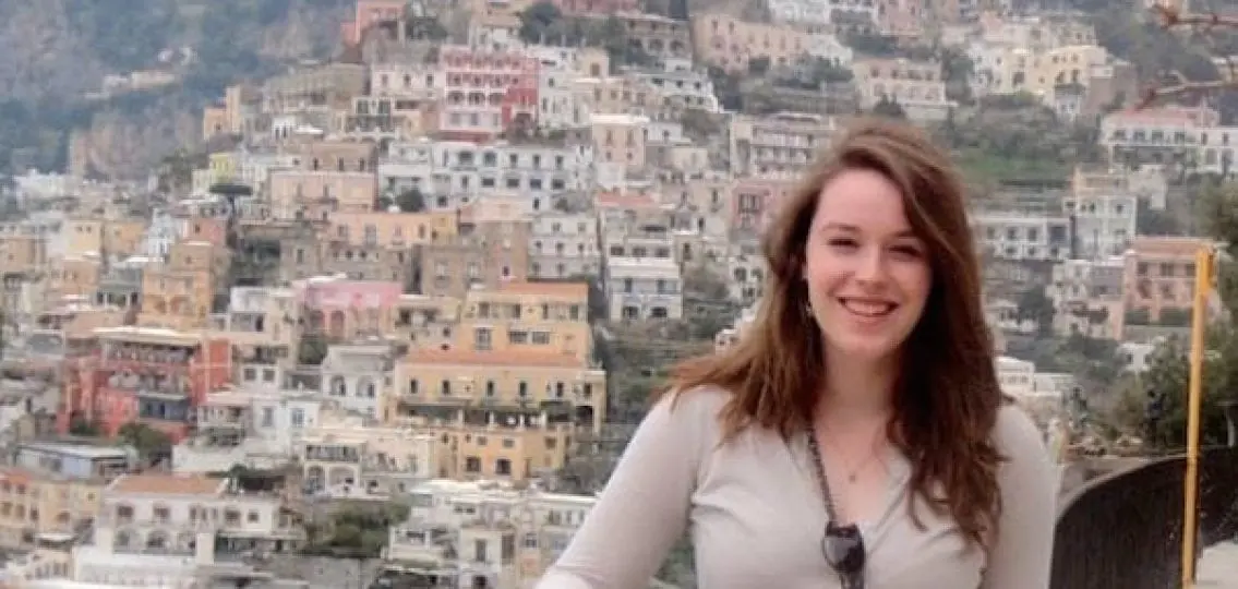 college student smiling and posing in front of an italian city