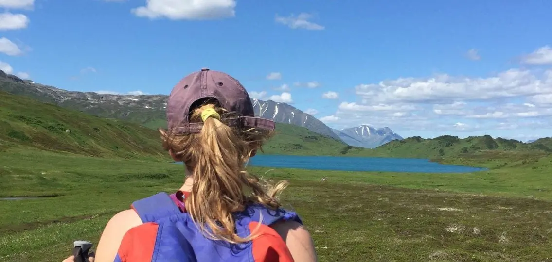 teenager hiking in alaska looking at a lake
