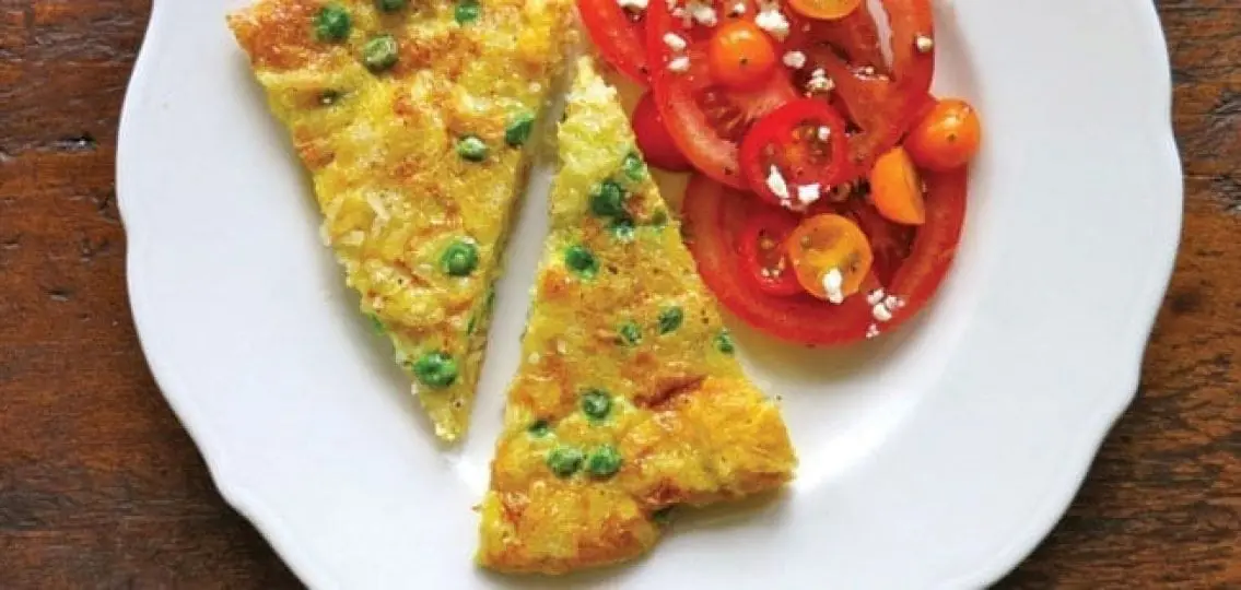 crispy rice omelet with side of tomatoes on a plate
